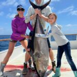 Family holding large tuna on fishing boat